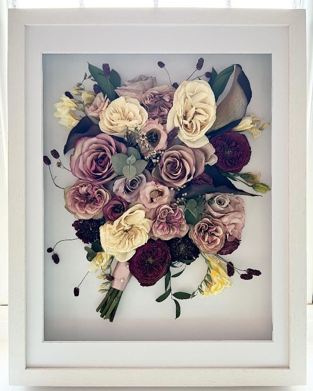A purple and white bouquet preserved in a frame