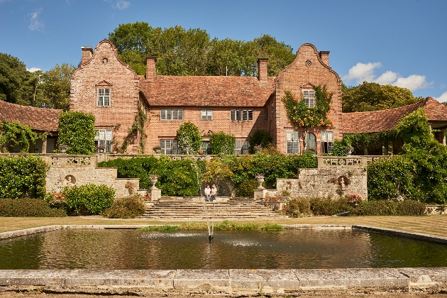 The exterior of a large orange building with a pond in front of it