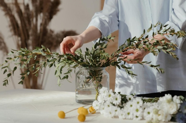 woman's hand moving flowers in a vas about