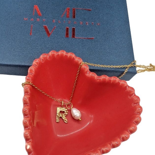 A gold necklace in a red heart-shaped bowl