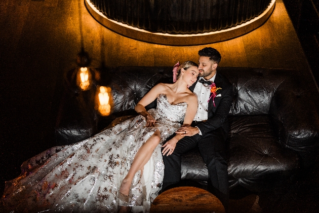 A bride and groom embracing while sitting on a sofa