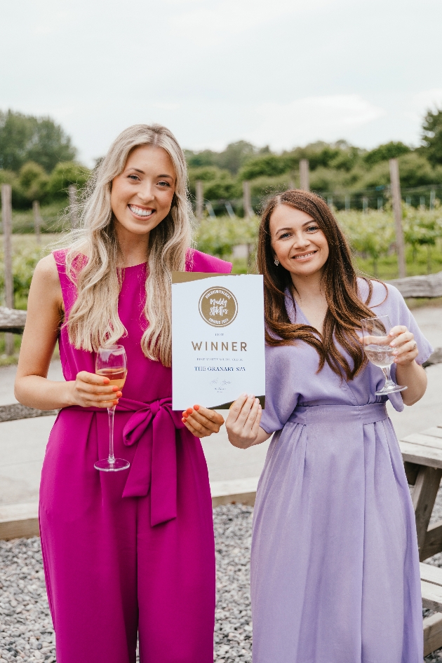 Two women holding glasses of drink while holding a sign that says winner