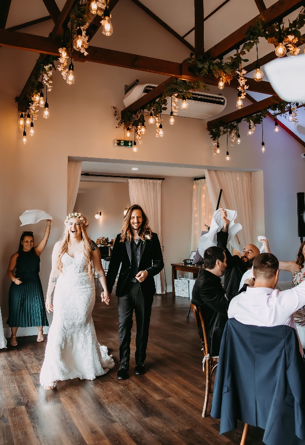 A bride and groom walking into a room while laughing