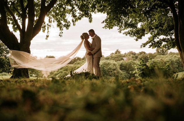 A bride and groom kissing in a woodland