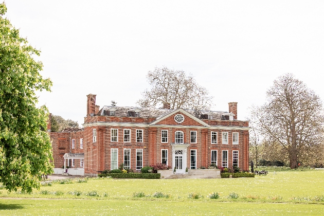 The exterior of a large manor house surrounded by grass