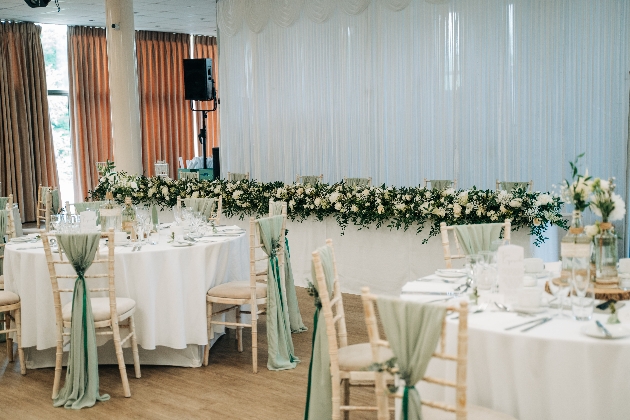 Two round white tables next to a long table all decorated with flowers