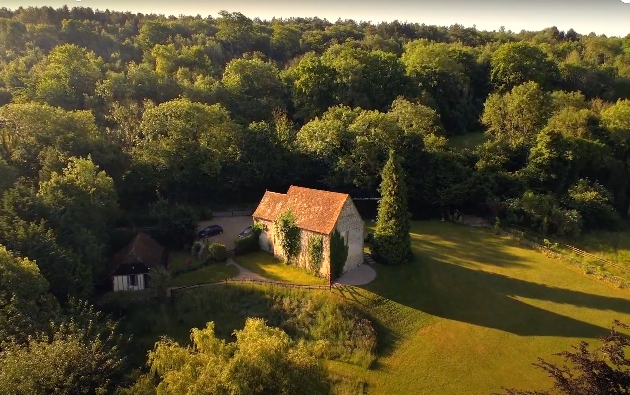 A sky view of a church-like building surrounded by trees