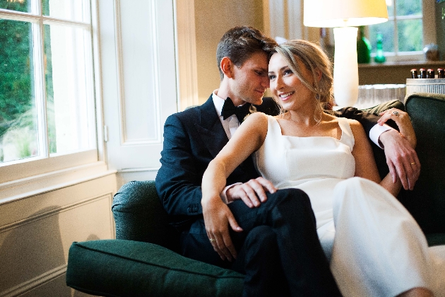 modern bride and groom sat on a chair together