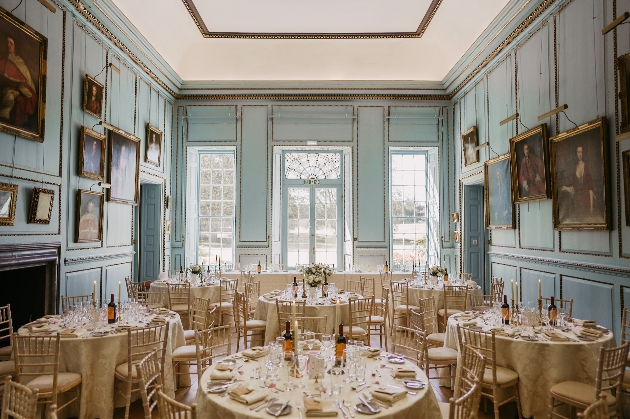 A green room with photos on the walls and round tables in the centre