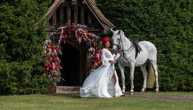 A bride standing next to a white horse