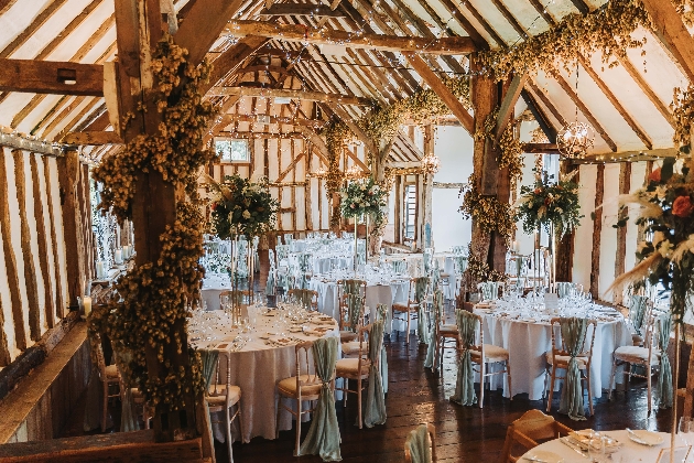 A barn full of white, round tables and flowers