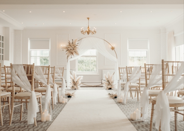 A light room with a white flower arch and chairs