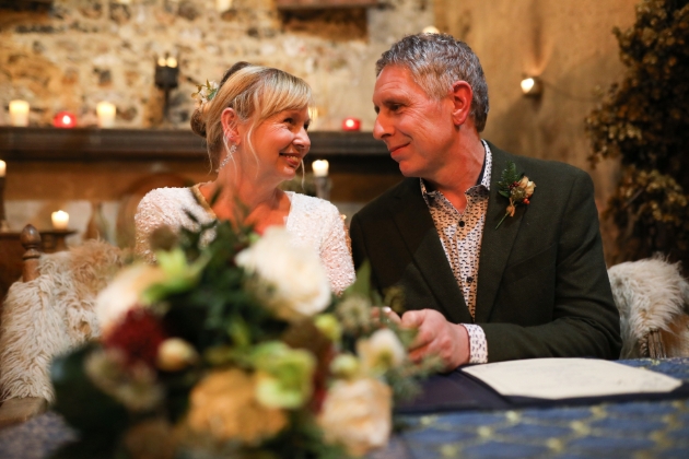 A bride and groom smiling at each other while sitting at a table